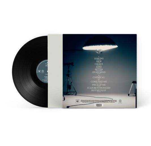 MK - In The Night Again - Vinyl. A vinyl record partially pulled from its sleeve, showing the black record and the back cover artwork with a studio scene and track list on a white background.