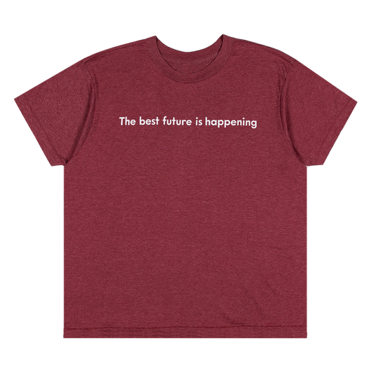A heathered burgundy short-sleeve t-shirt with the phrase 'The best future is happening' printed in white sans-serif text across the chest, displayed on a solid white background.