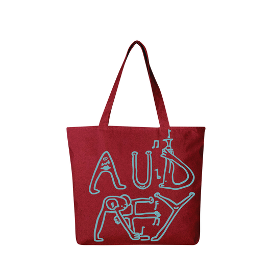 Front-facing view of a red tote bag featuring blue, doodle-style text that reads “Audrey Hobert”.